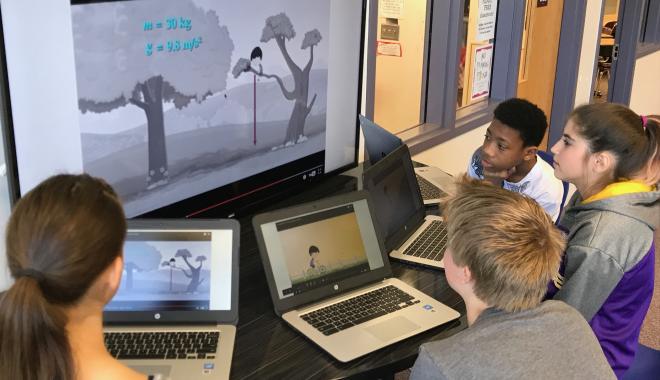 students working with laptops around a smart board