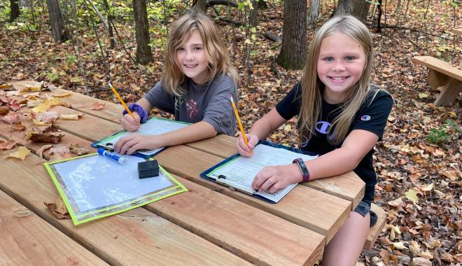 students at picnic tables in forest