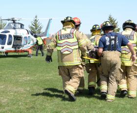Firefighters carry a mock crash victim to a medical helicopter