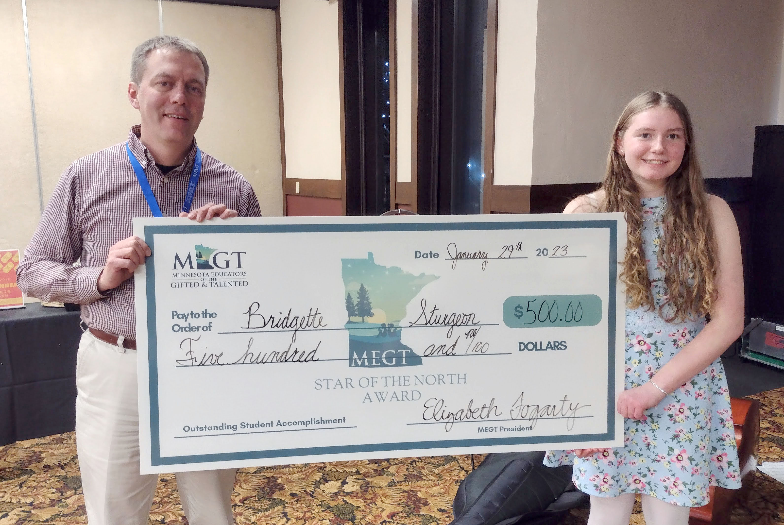Student and teacher hold scholarship check