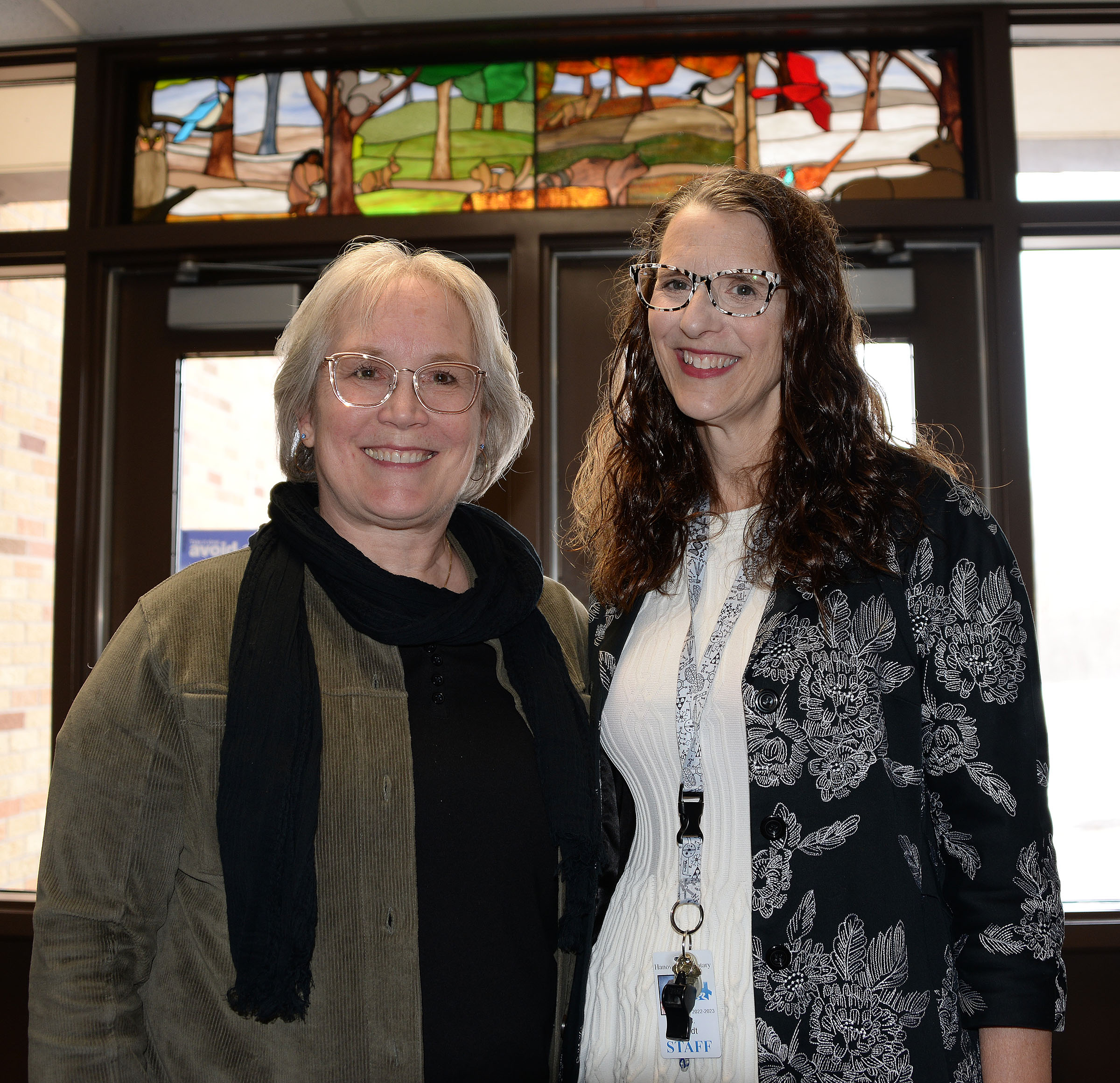 Artist and teacher stand under stained glass window