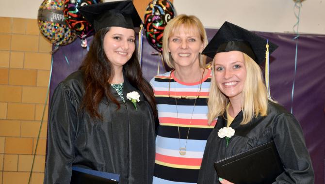 Two graduates with teacher