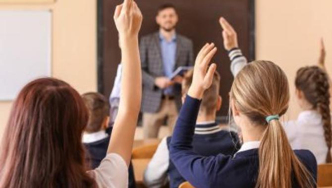 Students raising hands in classroom