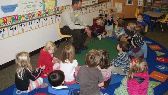 Parent volunteer reading to students