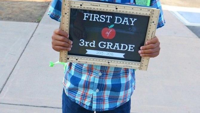 boy holding first day of 3rd grade sign