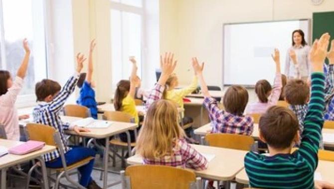 students raising hands in classroom