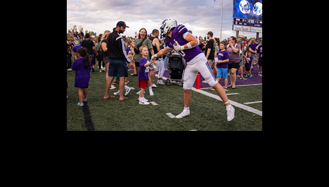 Kindergartner and football player shake hands