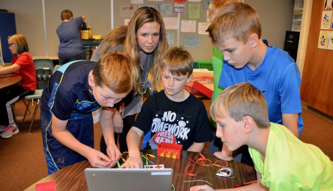 teacher working with students on a computer