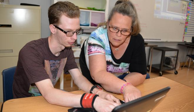 teacher with a student at a computer