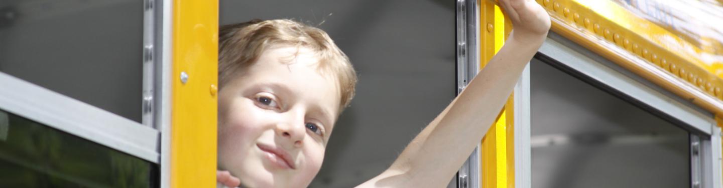 child waving from bus