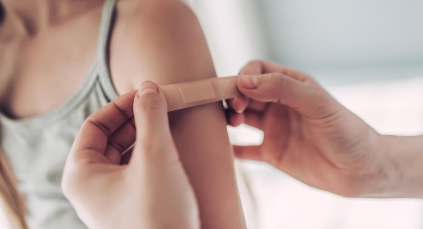 applying bandaid on child's arm