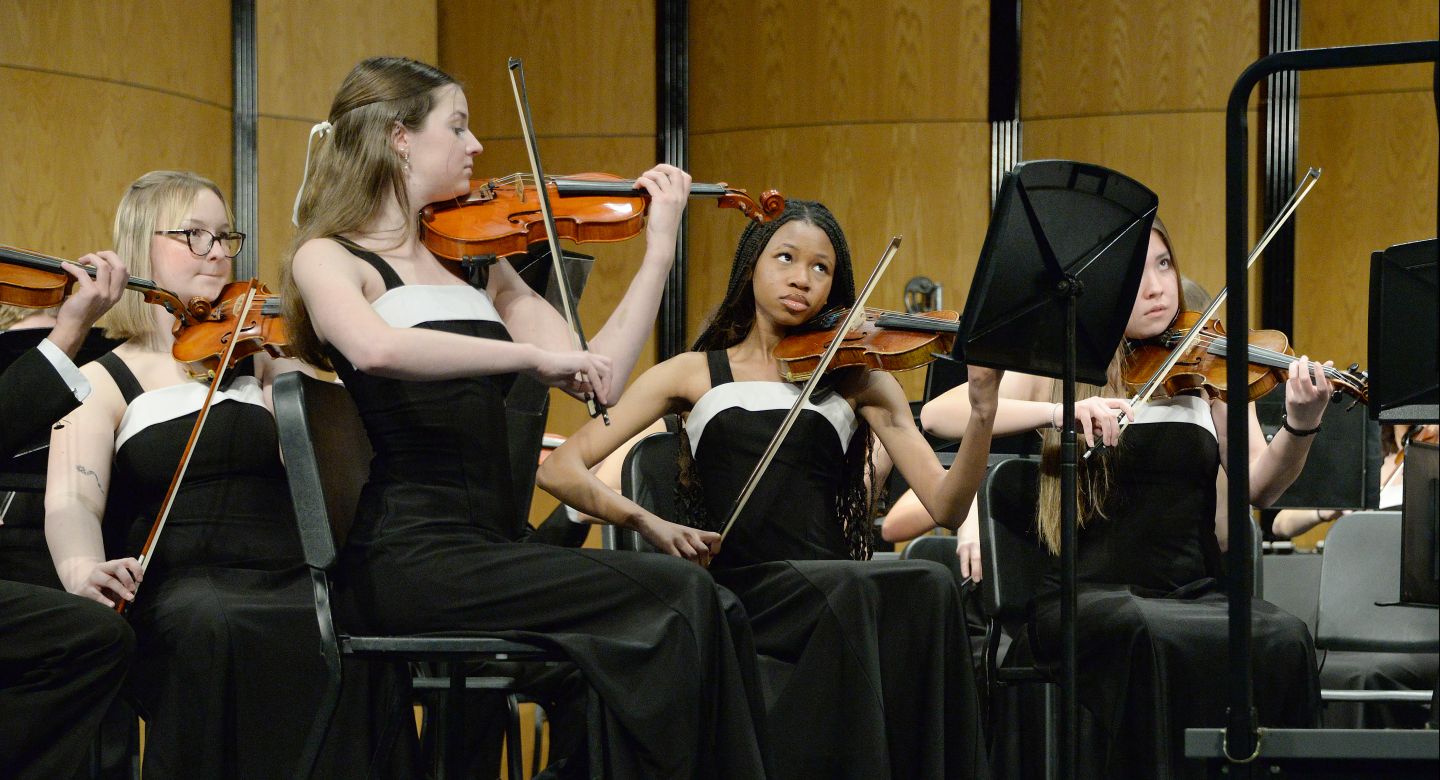 Violin players watch conductor