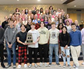 Orchestra members hold trophy