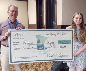 Student and teacher hold scholarship check