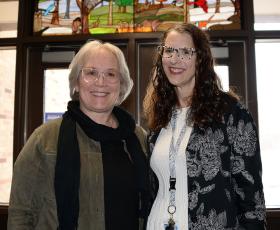 Artist and teacher stand under stained glass window